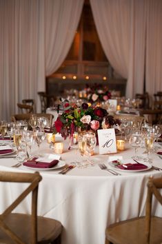 the table is set with wine glasses and place settings for guests to sit down at