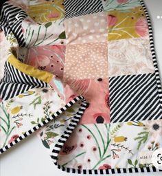 a patchwork quilt is laying on top of a white table with black and white stripes