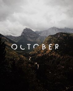 an image of the words october in front of some mountains and trees on a cloudy day