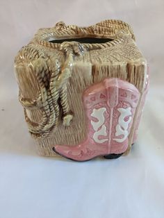 a cowgirl's boot is sitting on top of a wooden block with white and pink accents