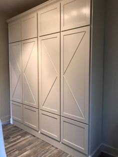 an empty room with white cupboards and wood flooring in the middle of it