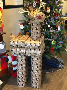 a chair made out of wrapped presents in front of a christmas tree with reindeers on it