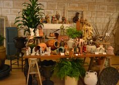 there are many vases and figurines on display in the room with plants