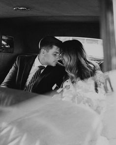 a man and woman sitting next to each other in a car, looking at each other