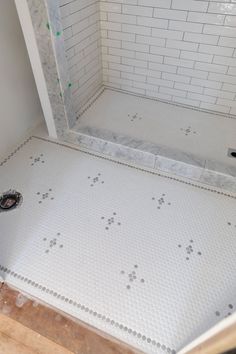 a bathroom with white tile and gray grouting on the floor, including a shower stall