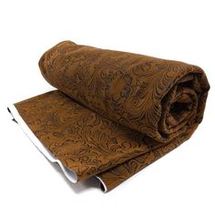 a rolled up piece of brown fabric on top of a white surface with an orange and black paisley pattern