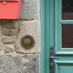 a green door with a round metal handle on it's side next to a brick building