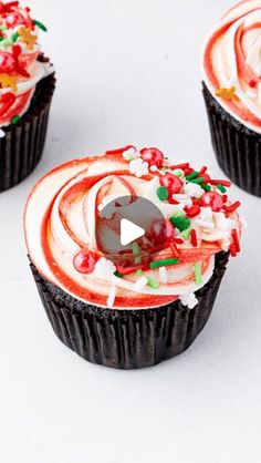 three cupcakes decorated with white frosting and red sprinkles on top