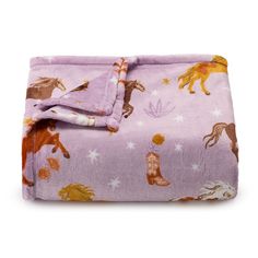 a purple blanket with horses on it and stars in the sky around it, sitting on top of a white surface