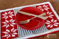 a red plate and silverware on a placemat