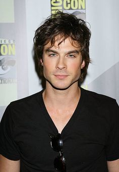 a young man with dark hair and sunglasses at a comic convention in front of a white background