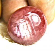 a close up of a person holding a pink bead