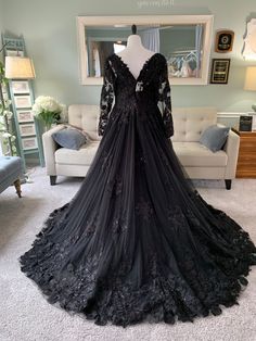 a black wedding dress is on display in a room with white carpet and couches