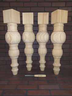 four wooden candlesticks are lined up against a brick wall