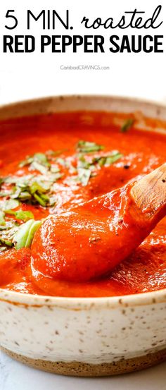 a close up of a bowl of red pepper sauce with a wooden spoon in it