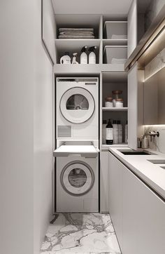 a washer and dryer in a small room with white cabinets, marble flooring