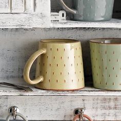 two coffee mugs sitting on top of a shelf