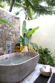 a bath tub sitting on top of a black and white rug next to a stone wall