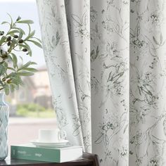 a vase with flowers on top of a table next to a window sill in front of a window