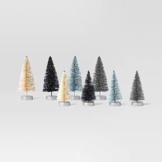 a row of small christmas trees sitting next to each other on top of a white surface