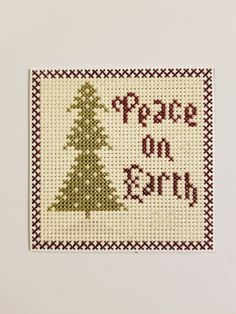 a cross stitch christmas tree with the words peace on earth