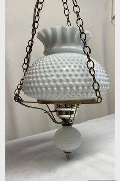 a white lamp hanging from a chain on top of a table