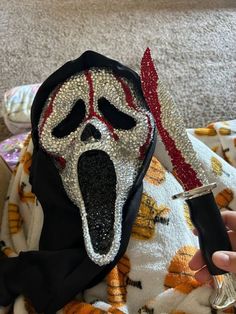 someone is holding a knife in front of a cloth with a scream mask on it