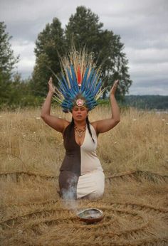 a woman sitting in the middle of a field with feathers on her head