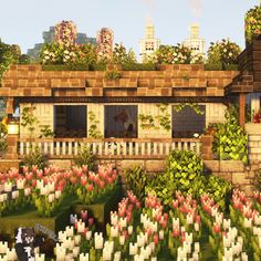 a house surrounded by lots of flowers in the middle of a park with trees and buildings