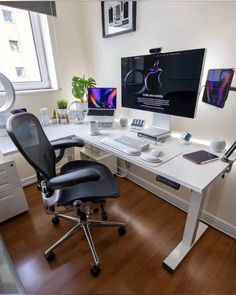 a computer desk with two monitors and a laptop on it in front of a window