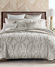 a bed with white and grey comforters in a bedroom