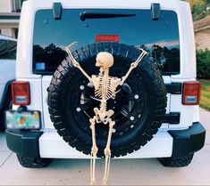 a skeleton is standing in front of a white jeep