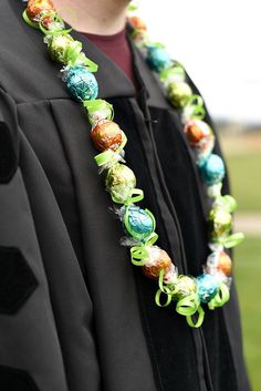 a person wearing a black graduation gown with green and blue decorations on it's neck