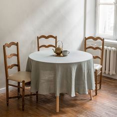 a white table with two chairs and a tea pot on top of it, next to a radiator