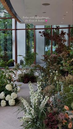 an indoor garden with lots of flowers and plants in the center, surrounded by large glass windows