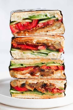 four grilled sandwiches stacked on top of each other with peppers and cucumbers