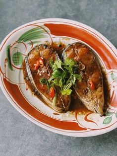 an orange and white plate topped with clams on top of a gray countertop