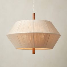 a white lamp hanging from a ceiling with a light shade on it's side