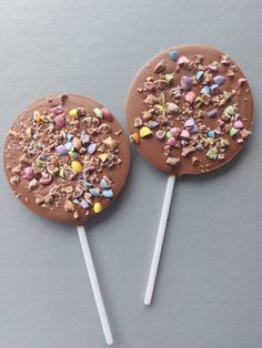 two chocolate lollipops covered in candy and sprinkles