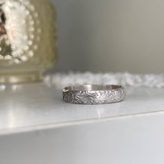 Our Cora Vintage Band is reminiscent of the old-world wedding bands of the past. It's a perfect addition to your ring stack! Mix and match from our collection of simple to delicately detailed bands. All designed to look perfect worn together in whatever combination you choose to create! This ring is hand-made in our studio at the time of order of sterling silver. Choose from a bright silver finish or oxidized to bring out the detail in the design, 4mm wide band. You're going to love creating you Classic Promise Toe Rings, Timeless Stackable Engraved Wedding Ring, Heirloom Sterling Silver Stackable Jewelry, Classic Toe Ring For Promise Occasion, Classic Toe Ring For Promise, Vintage Engraved Stackable Round Ring, Engraving Option Round Band For Promise Ring, Heirloom Stackable Midi Rings, Timeless Silver Stackable Bands