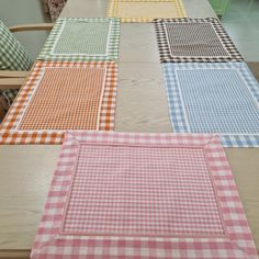 four different colored placemats sitting on top of a wooden table with green cabinets in the background