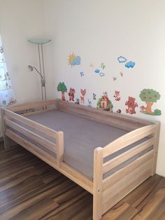 a wooden bed frame in the corner of a room with wall stickers on it