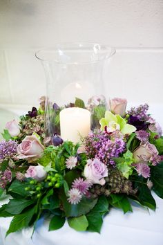 a vase filled with flowers and candles on top of a white tablecloth covered table