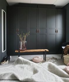 a room with black cabinets and white blankets on the floor, two vases filled with flowers