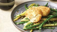 a plate topped with green beans and scallops next to a glass of wine