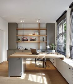 a home office with wooden floors and built - in shelving