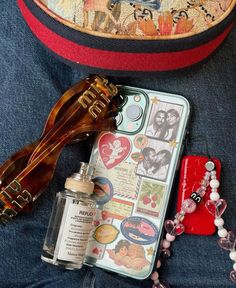 the contents of a purse and sunglasses are laid out on a blue jean jacket with an embroidered bag behind it