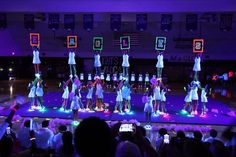 a group of young people standing on top of a basketball court holding up neon signs