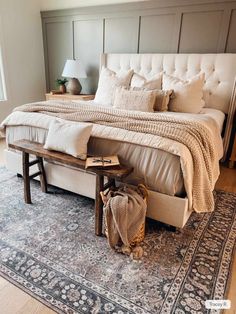 a large bed sitting on top of a rug next to a wooden table and lamp