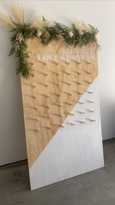 a large wooden sign sitting on top of a cement floor next to a white wall